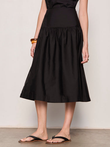 Person wearing a black skirt against a plain background