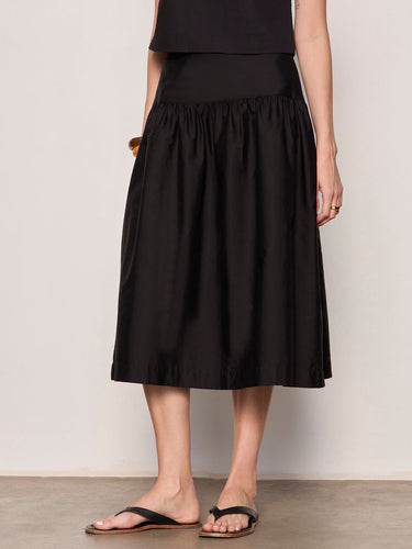 Person wearing a black skirt against a plain background