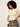 A woman with curly dark hair wearing a cream ribbed short-sleeve polo crop top and olive green plaid trousers, posing against a light off-white studio background.
