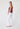 Woman wearing a mauve top and white pants on a white background