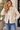 A woman wearing a multi textured jacket with fuzzy and ribbed textures outside.