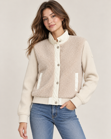 A woman wearing a multi textured jacket with fuzzy and ribbed textures on a white background.