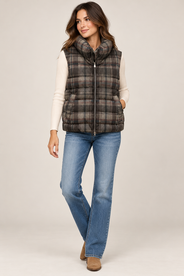 a woman wearing jeans, a white long sleeve top and a plaid vest on a white background.
