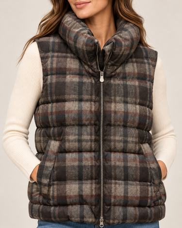 a woman wearing jeans, a white long sleeve top and a plaid vest on a white background.