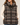 a woman wearing jeans, a white long sleeve top and a plaid vest on a white background.