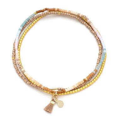 Multicolored beaded bracelet with tassel charm on a white background