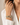 A close-up of a woman's wrist wearing a stack of multi-strand beaded bracelets, paired with a white collared shirt against a soft neutral background.