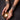 Hands holding a decorative candle holder with a lit candle, wearing beaded bracelets on a dark background.