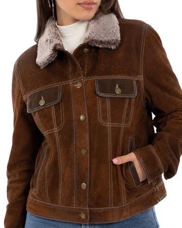 A woman wearing a distressed suede jacket with a faux fur collar and blue jeans on a white background