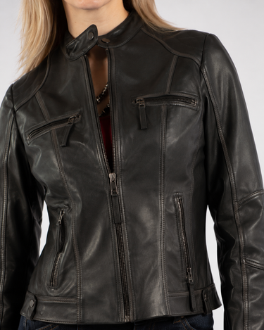 a woman wearing a black leather jacket with a vintage feel and zipper detailing with blue jeans on a white background
