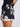 Black shorts with white floral pattern worn by a person on a light gray background