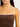 Woman wearing a brown ribbed tank top with thin white straps on a plain background