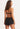 A woman facing backwards wearing a bikini top and black shorts