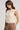 A woman wearing an oat colored crochet floral top and beige pants