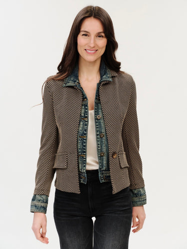 A woman wearing a mixed media jacket that included an inner lining of a denim jacket and the outer layer of a checkered blazer on a white background.