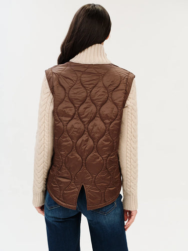 A back view of a woman wearing a mixed media jacket that consists of a brown vest and knit sleeves and collar on the jacket.