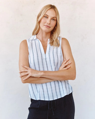 Woman wearing a sleeveless striped shirt against a plain background