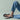 Person wearing black flip-flops and blue jeans on a light green background