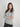 a woman wearing a light grey charcoal sweater with black jeans on a white background