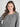 A woman modeling a heather gray long-sleeve henley top with a button placket Against a light grey studio wall
