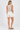 Woman wearing a beige sleeveless top and white shorts on a plain background