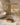 Gold hoop earrings displayed on a gold stand, set on a marble surface with neutral decorative props in the background.