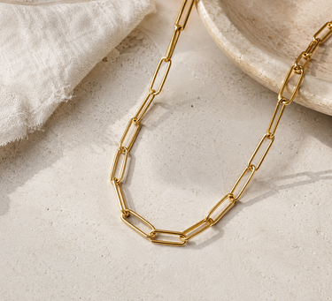 A gold chain necklace on a textured table
