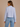 Woman wearing a light blue striped shirt and jeans on a beige background