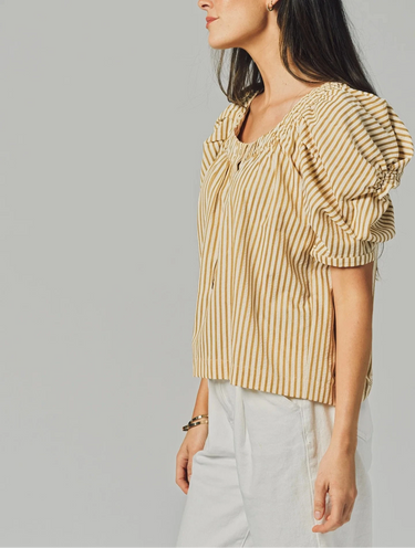 Woman wearing a yellow striped blouse with puffed sleeves against a gray background