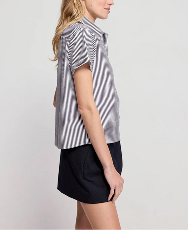 Woman wearing a black and white striped shirt and black shorts on a light gray background