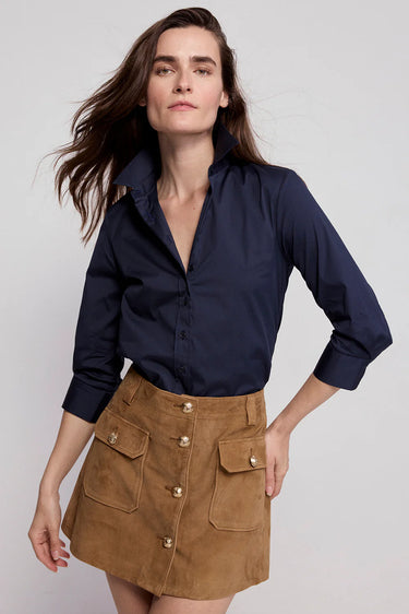 Woman wearing a navy shirt and brown skirt on a white background