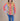 Person wearing a colorful shirt with a beige vest over a red and blue striped shirt, on a beige background.