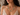 A close-up of a woman wearing a colorful beaded necklace with green, yellow, pink, and white round beads, paired with a cream lace camisole top.