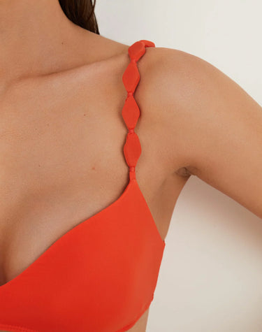 Close-up of a red bikini top with thin straps on a white background