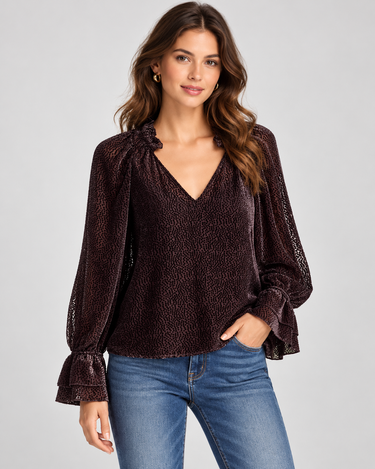 A textured black dot sheer chocolate blouse with blousy sleeves and blue jeans.