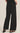 Person wearing black wide-leg pants on a beige background