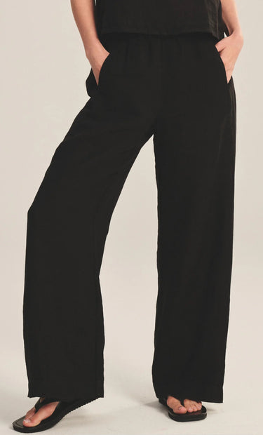 Person wearing black wide-leg pants on a plain background