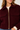A close-up of a woman wearing a burgundy sherpa fleece zip-up jacket with a gold zipper and flap pockets over a cream ribbed sweater.
