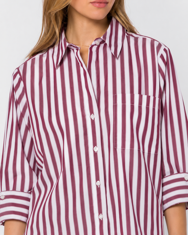 A close-up of a woman wearing a long-sleeve button-front shirt with vertical burgundy and white stripes, a pointed collar, and a chest pocket.