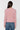 A woman shown from the back wearing a fuzzy, textured light pink long-sleeve sweater and blue jeans against a plain white background.