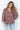 Multicolor abstract print V-neck blouse with long sleeves and button cuffs, styled with light-wash jeans on a model.