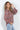 Multicolor abstract print V-neck blouse with long sleeves and button cuffs, styled with light-wash jeans on a model.