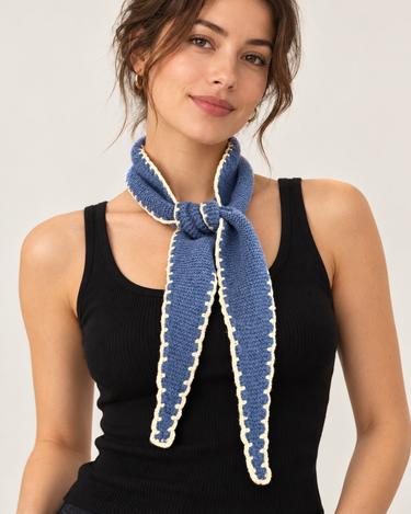 a woman wearing a cashmere knit scarf in Baltic blue with off white stitching.