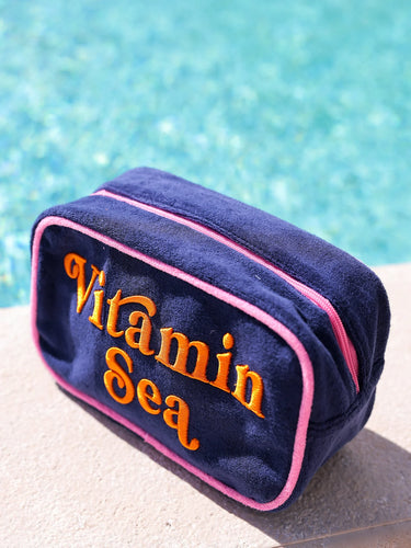 Navy blue pouch with 'Vitamin Sea' text by a pool