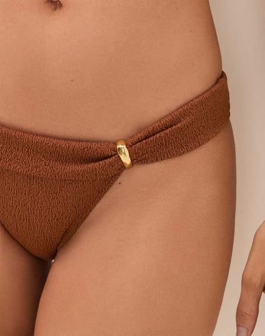 Brown bikini bottom with a gold clasp on a beige background