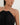 Woman wearing a black halter neck dress with a white beaded necklace on a plain background