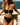 Woman wearing a black bikini with green accents by the ocean.