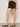 A woman wearing mid rise rich brown shorts on a neutral background