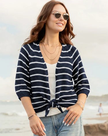 Woman wearing a navy and white striped cardigan on a beach