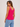 Woman wearing a bright pink ribbed tank top and blue jeans on a light background